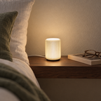 NIMI mini table lamp with warm light on a walnut bedside shelf