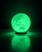 ORBIS RGB globe lamp glowing green on a dark studio background